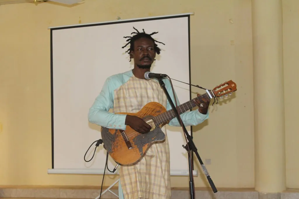 Le guitariste Modibo Konaté dit Van Guitare chante au micro, guitare en main.